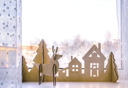 Christmas wooden house with Christmas trees and deer. New Year's decor on windows or shelf.の写真素材