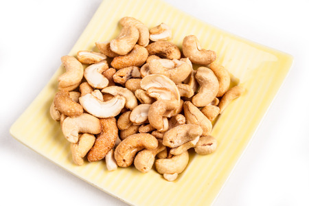 tasty cashew nuts with leaves, isolated on whiteの写真素材
