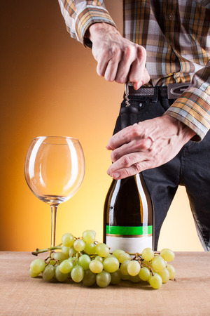 bottle of white wine and grapes on a wooden tableの写真素材