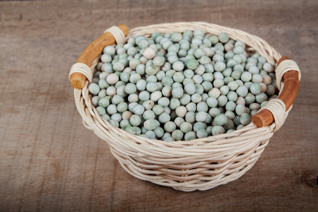 peas in a wicker basket on a wooden tableの写真素材
