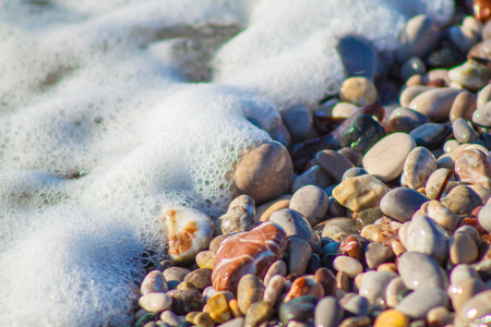 Colored pebbles on the beach and sea waveの写真素材