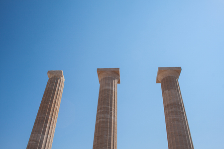 Columns on the hellenistic stoa of the Acropolis of Lindos, Rhodes, Greece, Blue sky, olive tree and...