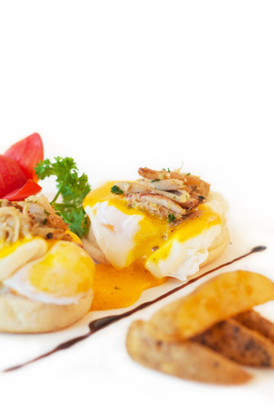 Poached egg with crab meat on english muffin, on white.の写真素材