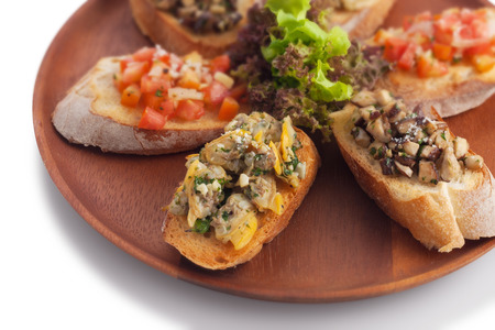 Medley bruschetta topping with sauteed mushroom/ garlic butter clam/ tomato salsa on wood plate, on white.の写真素材