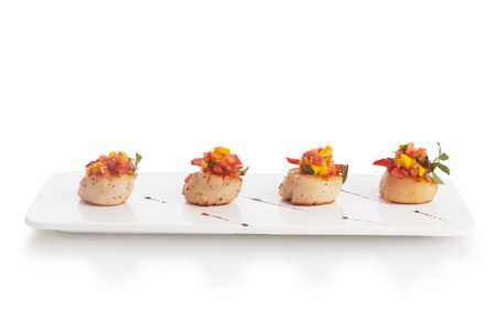Scallop soaked with fresh yellow mango salsa, isolated on white.の写真素材