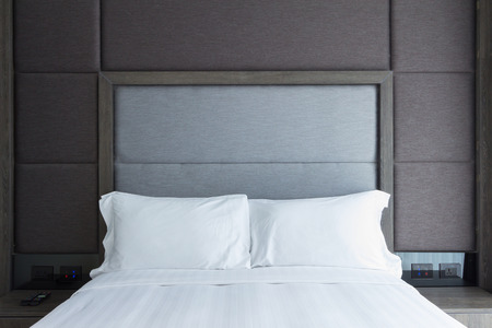 grey cloth headboard and white duvet bed.