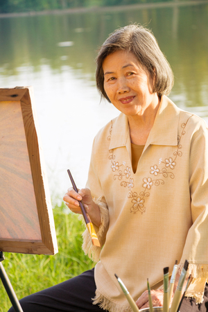 76 years old woman happy with painting in the park.の写真素材