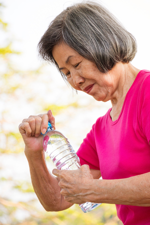 Asian senior woman opening a bottle of drinking water.の写真素材