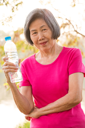 Asian senior woman smiling with a bottle of drinking water.の写真素材