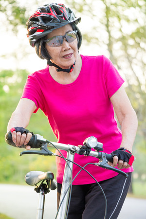 Portrait of asian senior woman wearing helmet ,standing with her folding bike.の写真素材