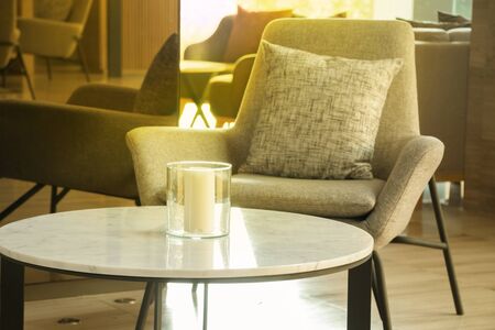 Morning light in lobby lounge with grey armchairs and round tables in modern residential building.の写真素材