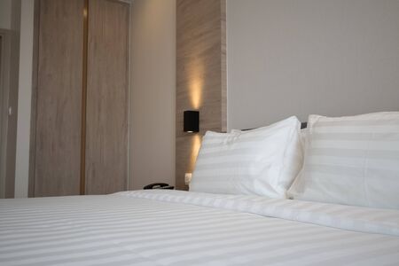 Modern interior hotel bed room with simply wood headbord and zen style cubic lamp.