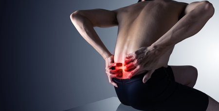 Man holding both hands on lower back pain ,inflamed backache with copy space.の写真素材