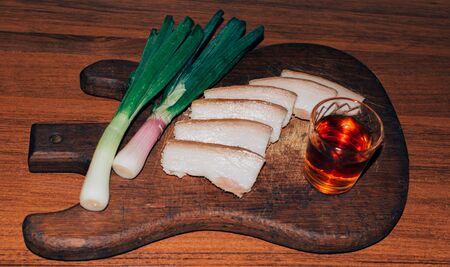 Ukrainian pork lard white bread onion and a glass of alcohol on a wooden surfaceの写真素材