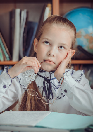 A little schoolgirl sits at a deskの写真素材