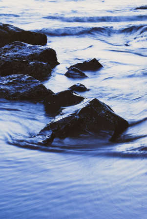 Black ocean rocks surrounded by the tideの写真素材