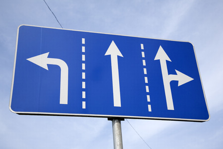 Three Way Direction Sign against Blue Sky Background