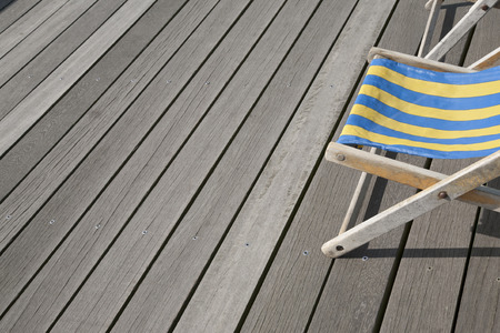 Blue and Yellow Deckchair against Wooden Boardsの写真素材