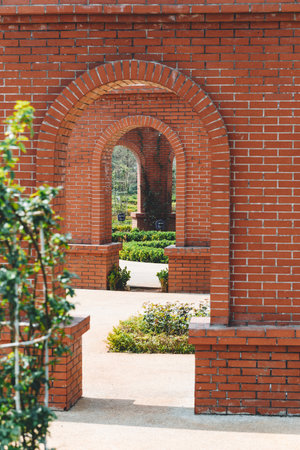 Brick arch in the park with red brick wall and green trees.の写真素材