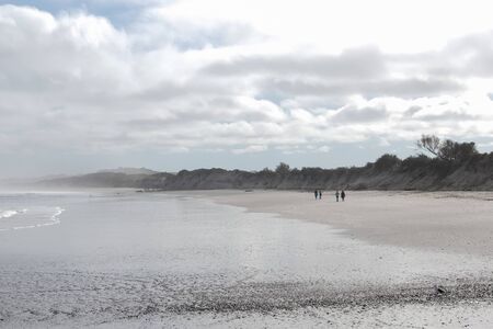 On an empty beach at Yzerfontein a group of walkers fade into the grey landscape in the morning...