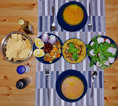 A vibrant table setting featuring various dishes, including Persian Abgoosht, salad, and snacks.