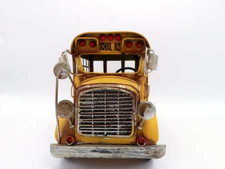 Front view of a vintage toy school bus with weathered detailing against a plain background.