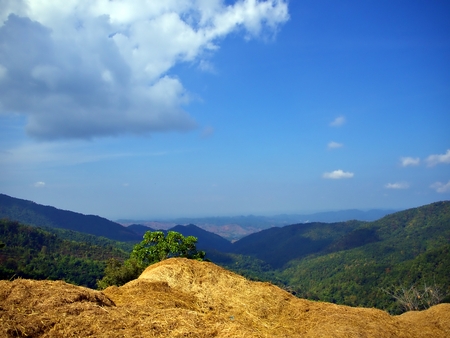 Landscape of green mountain with blue sky and pile of dry hay at the edge, Nan, Thailand.の写真素材