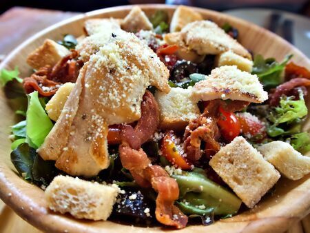 Close up shot on the caesar salad with cheese and bacon in the wooden bowlの写真素材