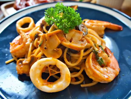 Seafood spaghetti with squid, prawn and mushroom on the blue plateの写真素材