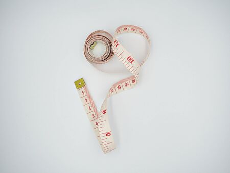 Isolated top shot on the losing measuring tape forming a spiral in white backgroundの写真素材