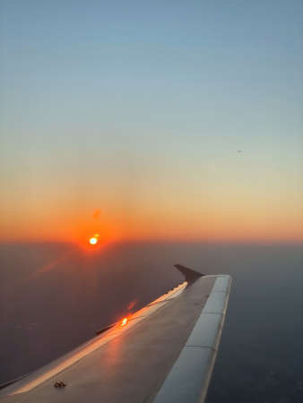 The air plane wing in the sky with sunset in the horizonの写真素材