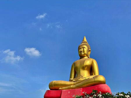 The big golden buddha with red base and the blue sky with cloudの写真素材