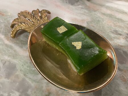 The thai style pandan steam layer cake (kanom chan) with a sheet of gold in the gold plateの写真素材