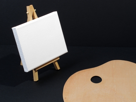 An image of paint brushes laying on a painters palette with an Easel in the backgroundの写真素材