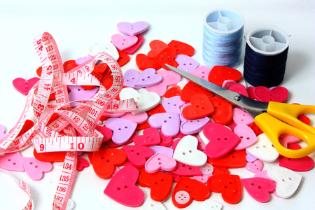 Pretty coloured heart shaped buttons with scissors and cotton reelsの写真素材