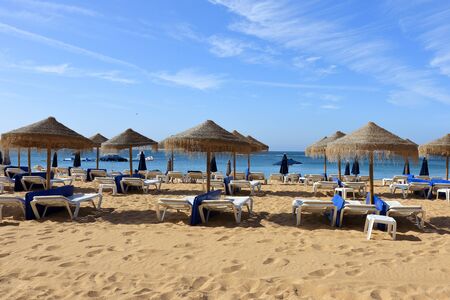 Straw umbrellas and deck chairs on the beach at Albufeiraの写真素材