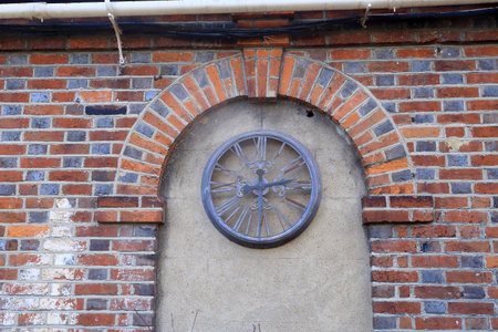 A rusty old clock face under a brick archの写真素材