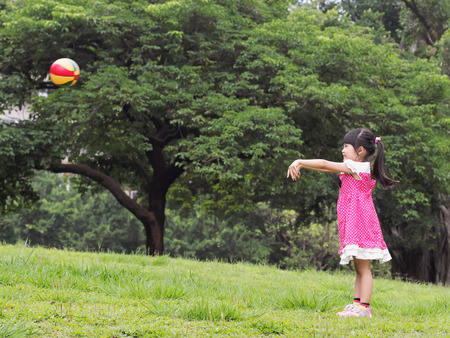 The girl playing the ball on the grass in the park の写真素材