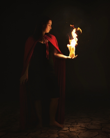 Woman holding a burning fire ball at night.の写真素材