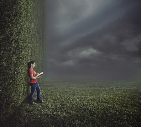 Surreal image of a grassy landscape with a woman reading a book.の写真素材