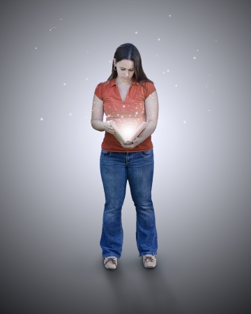 Woman holding a glowing book in her hands.の写真素材