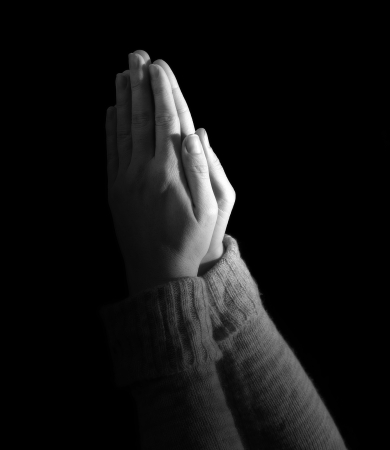 Woman's hands held up in prayer on black background.の写真素材