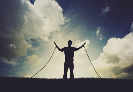 Man lifting hands in praise even though chained to the ground.の写真素材