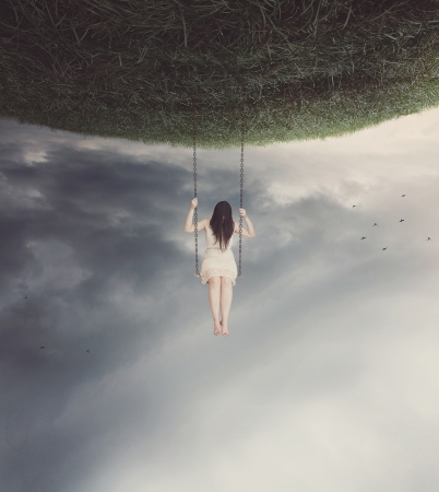 Sad woman swinging on a surreal swing.の写真素材