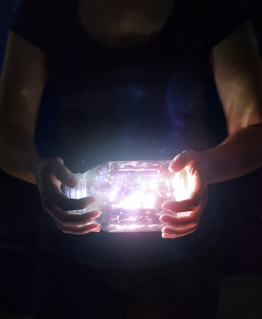 Woman holding a jar with bright glowing lights and colors.の写真素材