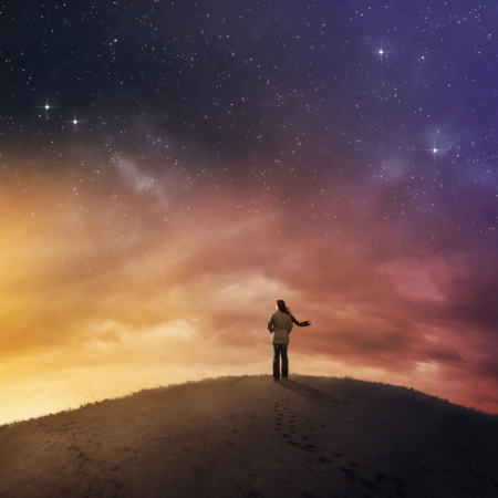 Woman standing in snow under starry night sky.の写真素材