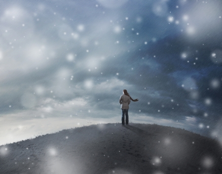 A woman standing on top of a hill in a snow stormの写真素材
