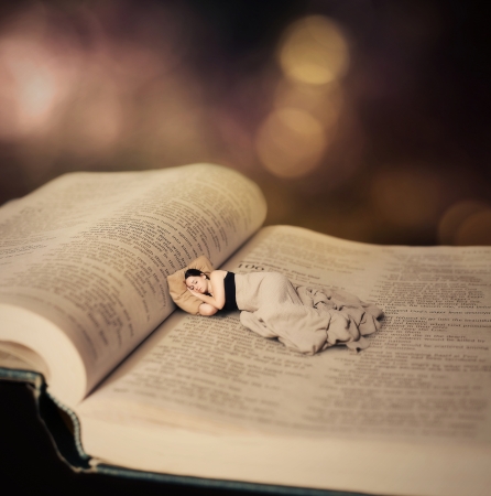 Surreal image of a woman sleeping on the pages of the Bible.の写真素材