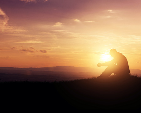 Man praying as the sun rises in the mountains.の写真素材