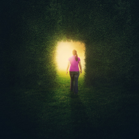 A woman walks through a door inside a grass wall.の写真素材